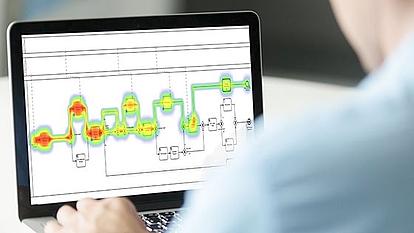 A person using a laptop displaying a workflow diagram with a heatmap overlay, indicating areas of high and low activity.